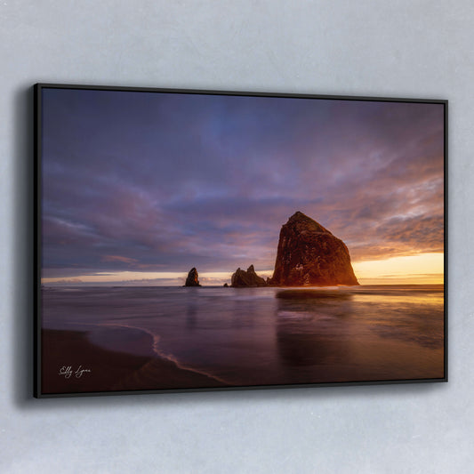 Haystack Rock at sunset on Cannon Beach with vibrant golden light reflecting on the ocean.