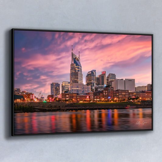 Fine art photo of the Nashville skyline at sunset with neon reflections and a glowing pink sky.