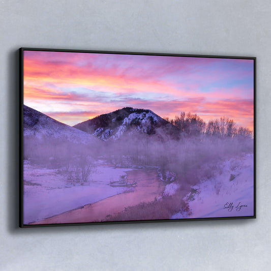 Sunrise over misty river and snowy mountain landscape in winter.